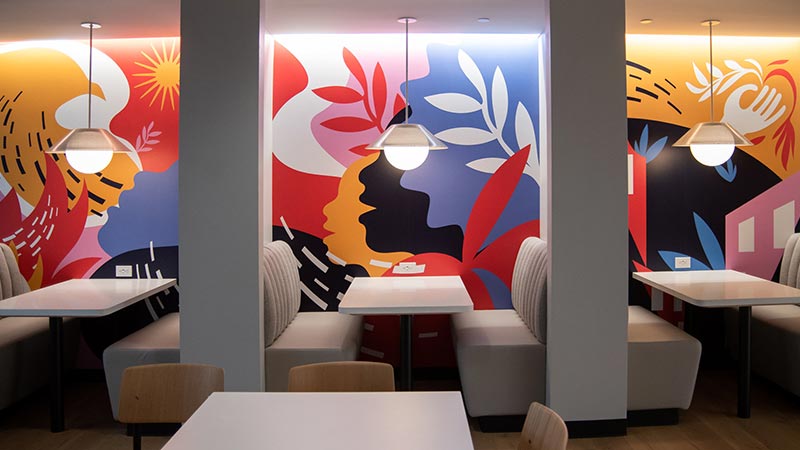 Three corporate booths with colorful mural backgrounds.