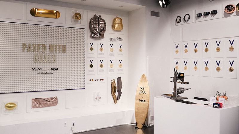 Pop up shop with gold and silver items displayed on the wall and a sign that reads Paved with Goals