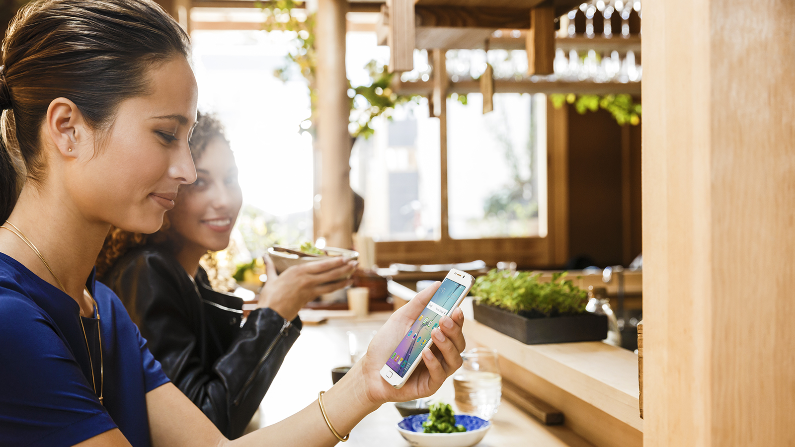 marquee-woman-restaurant-mobile-1600x900 Woman holding smart phone chatting with another woman at bar.