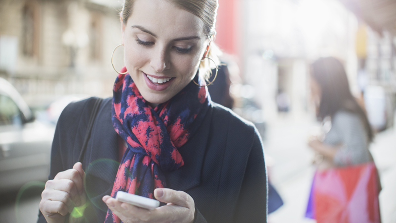 Woman using mobile phone on city street. Woman using mobile phone on city street.
