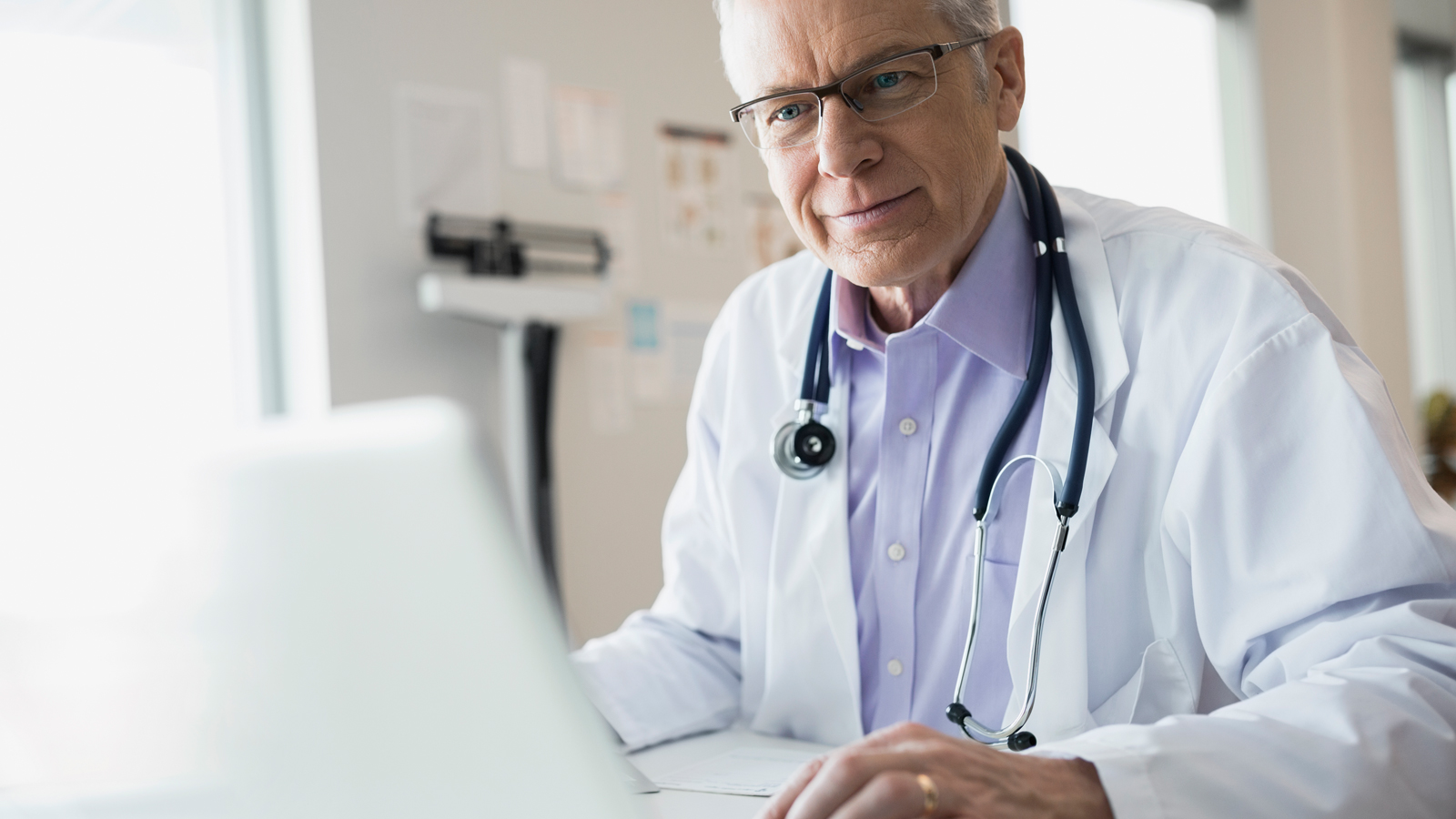 Doctor in office using laptop.