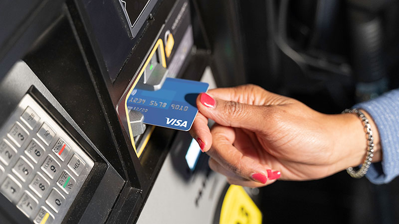 Woman's hand dipping a Visa chip-enabled card at a fuel pump