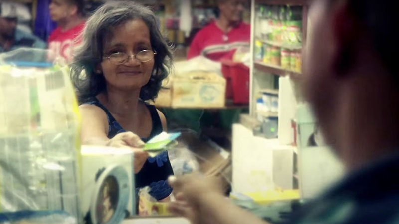 Woman behind a plexiglas divider paying with a credit card