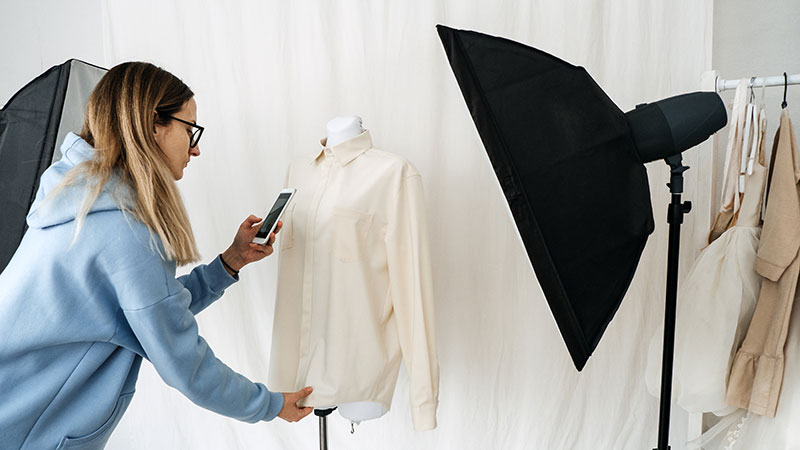 Photographer taking a picture of a shirt for a recommerce shopping website.