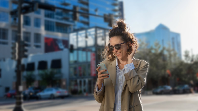woman wearing sunglasses, looking at her mobile phone