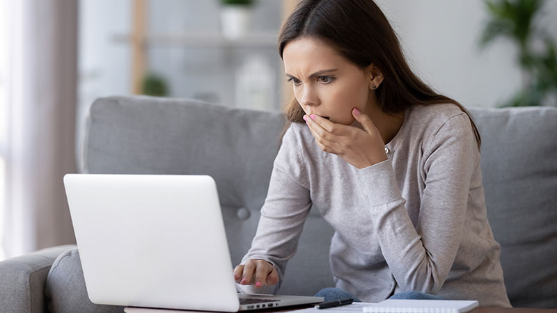 Woman looks at a laptop computer with a concerned look on her face.