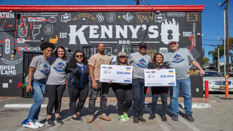 Kenny's BBQ employees holding grant checks outside of restaurant 