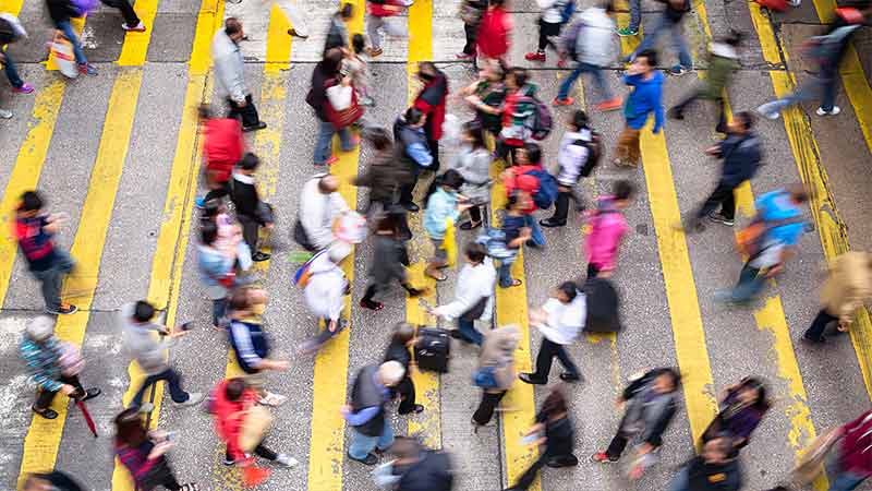 An overhead view of a crosswalk featuring multiple pedestrians. An overhead view of a crosswalk featuring multiple pedestrians.