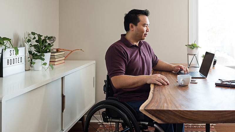 Asian Man In Wheelchair In Home Office.