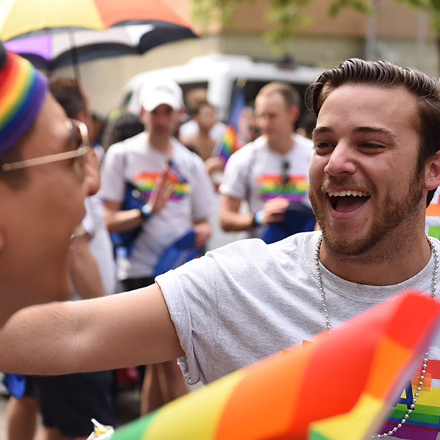 Men with rainbow flags and Visa shirts smiling and celebrating
