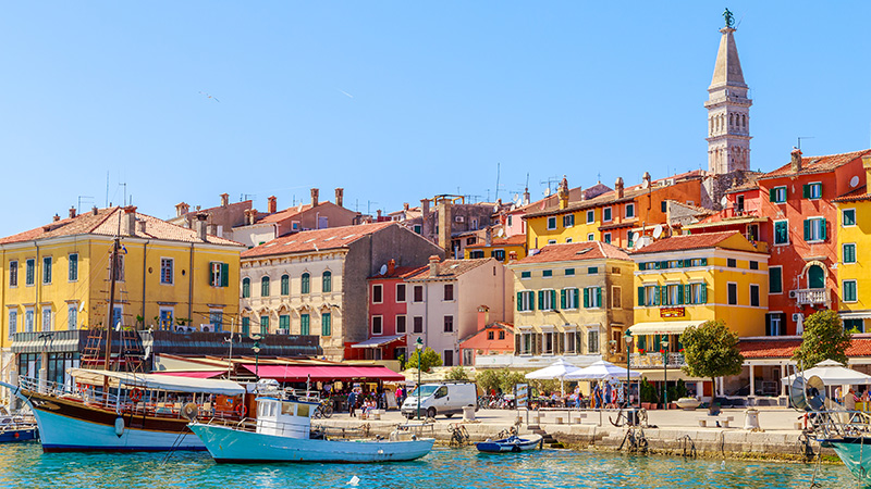 Image of a colorful town on the lake side with small boats.