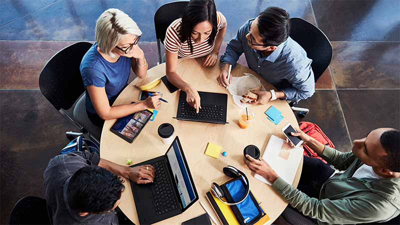 young-people-around-desk_800x450 Group of people in office sitting in a round table and discussing.