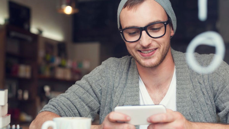 guy in coffee shop smiling looking at his phoone