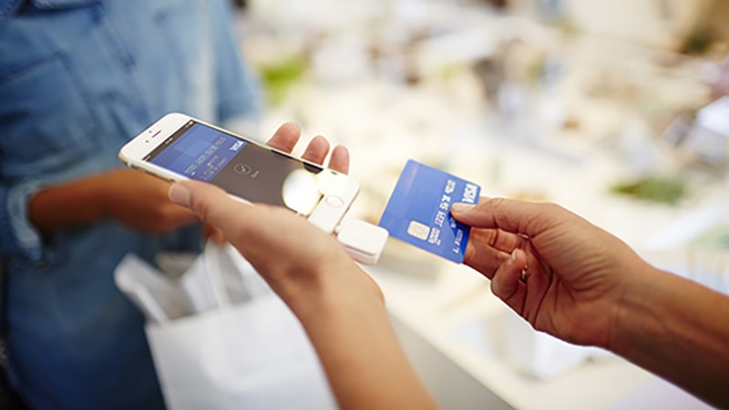 Merchant using Square Credit Card reader to swipe Visa card for purchase. Merchant using Square Credit Card reader to swipe Visa card for purchase.