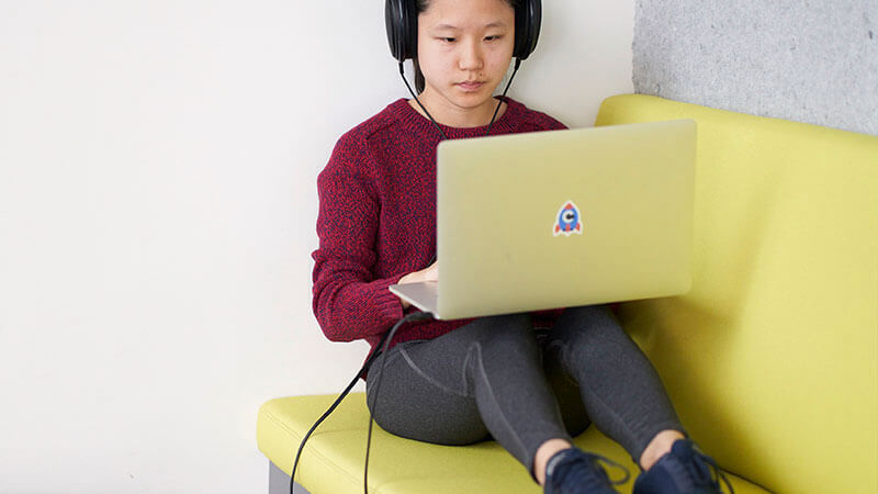A Chime employee working on a sofa with headphones.