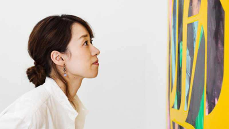 Woman standing in an art gallery, looking at an abstract modern painting Woman standing in an art gallery, looking at an abstract modern painting