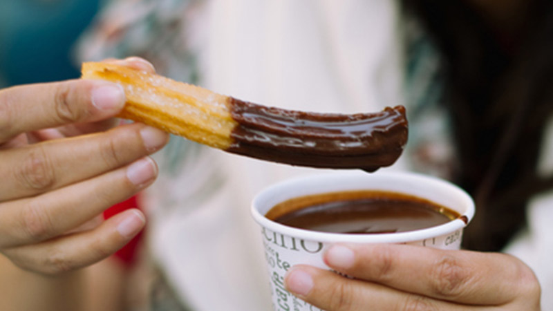 A churro dipped in hot chocolate A churro dipped in hot chocolate