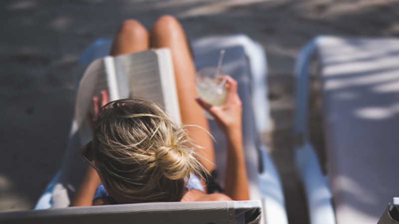 Woman sitting on lounge chair tanning Woman sitting on lounge chair tanning