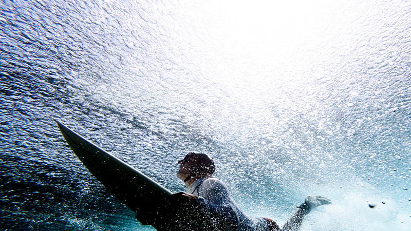 Surfer duck diving under reef break Surfer duck diving under reef break