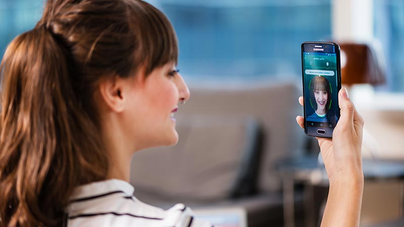 fighting-fraud-smile-800x450 Woman using smart phone to calibrate facial recognition.