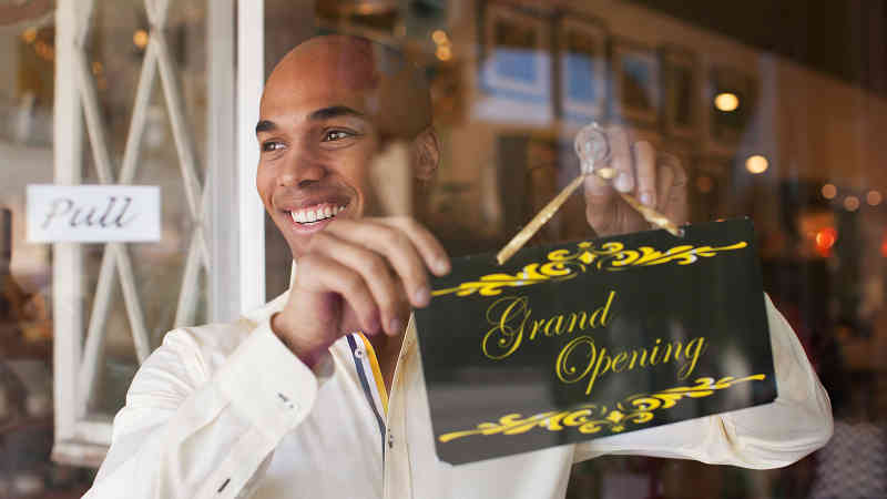 Businessman hanging Grand Opening sign in front window. Businessman hanging Grand Opening sign in front window.