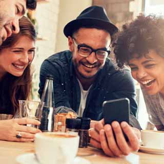 Grupo de amigos sorrindo para a tela de um smartphone