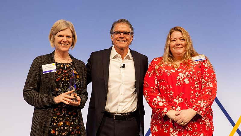 Three members of ITA Group onstage accepting the Client Achievement Award.