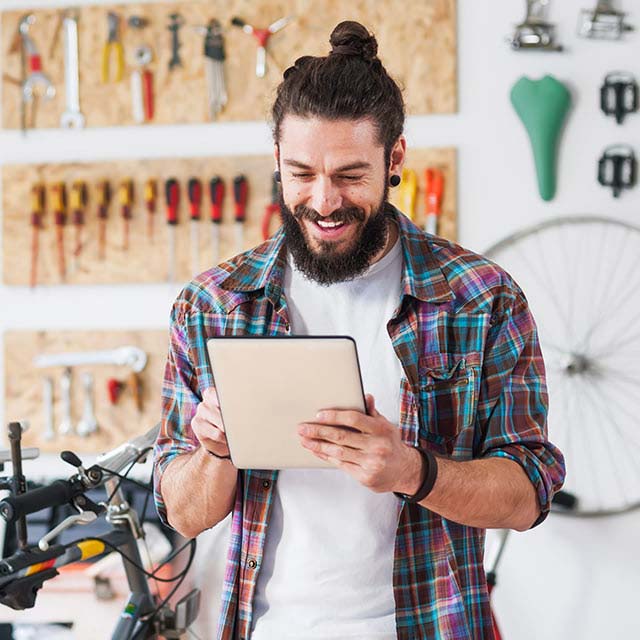 Smiling man looking at a tablet in his hands.