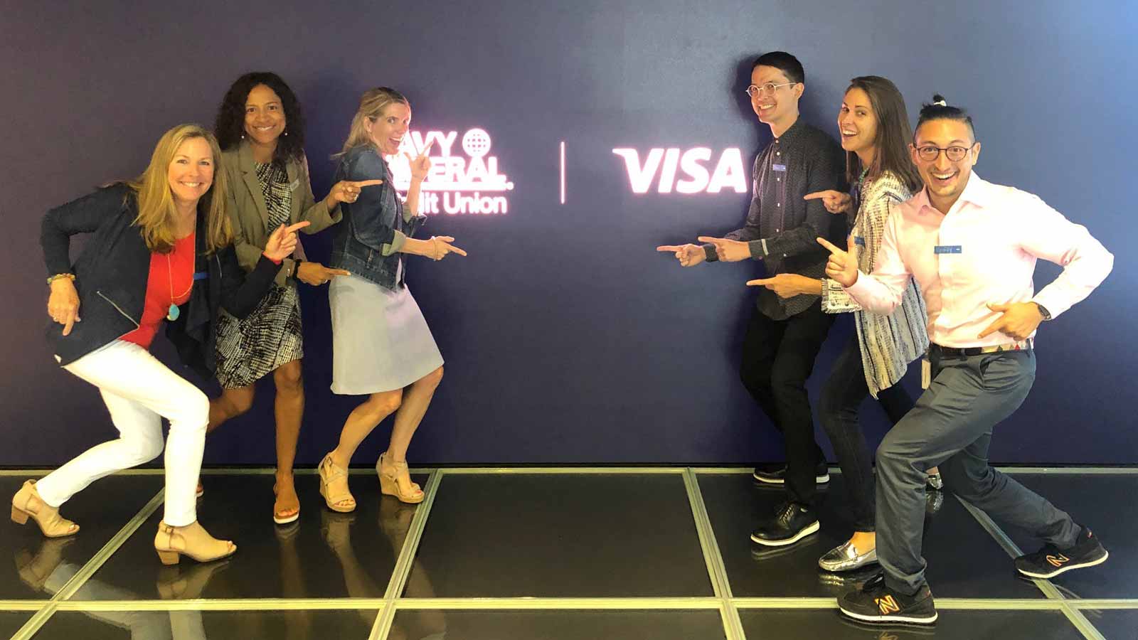 Black wall showing 'Navy Federal Credit Union' and 'Visa' flanked by the six winners from there, each striking a fun pose.