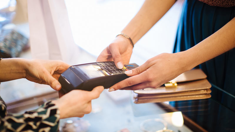 Female customer paying on credit card reader in boutique