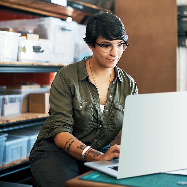 Young woman looking at a laptop while inside in a storage area.