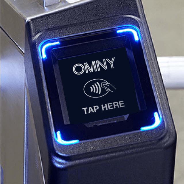 Close up of an OMNY card reader with text: OMNY TAP HERE and the tap to pay logo. 