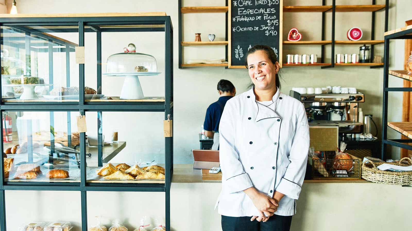 The female business owner of a bakery stands at the counter.