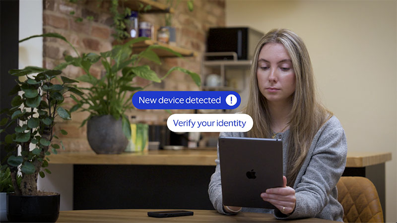 Woman using tablet with bubbles that say New device detected and Verify your identity.