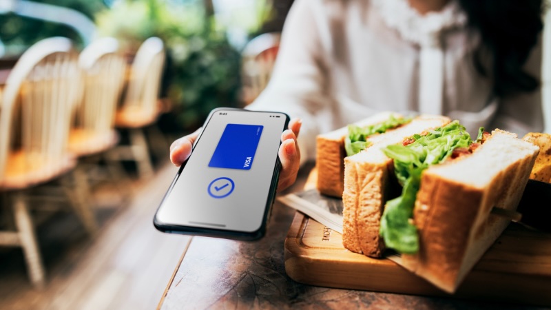 Woman holding phone, screen shows checkmark and blue Visa card.