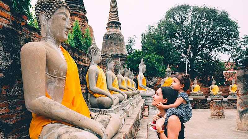 A mother and daughter admire Buddha statues at a temple in Thailand.