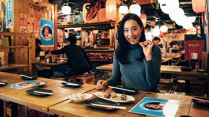 Woman enjoying street food in Tokyo, Japan.