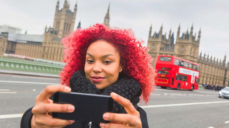 A fashionable woman takes a selfie outside a London landmark.