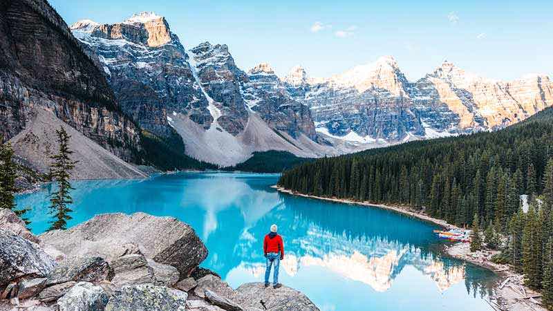 Man at Moraine Lake at sunrise in Banff, Canada.