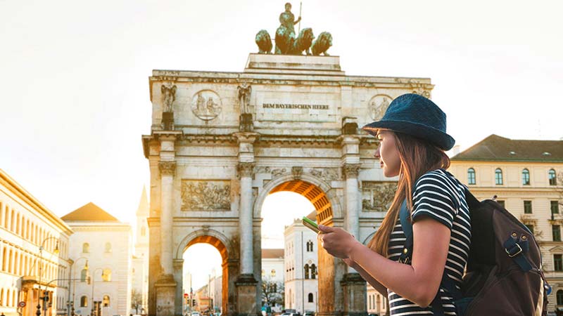 A female traveler stands in front of the Victory Gate in Munich, Germany.