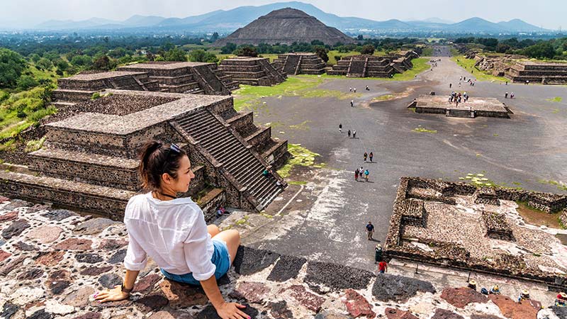 A young woman relaxes atop an ancient pyramid in Mexico.