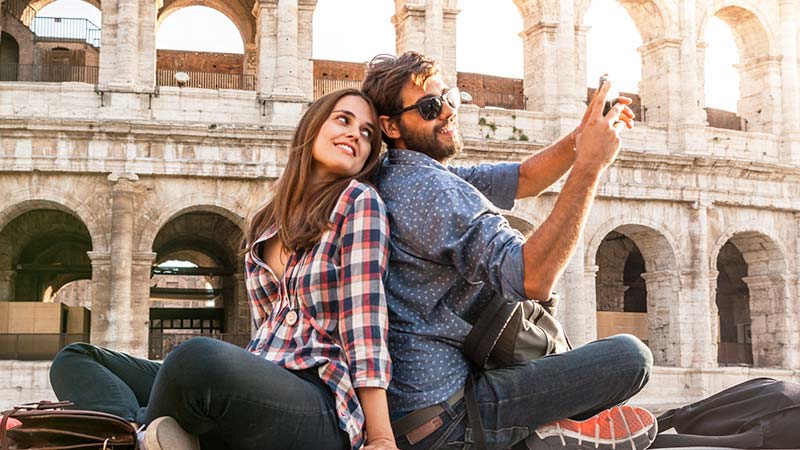 A man and woman taking picture at the Roman Colosseum.