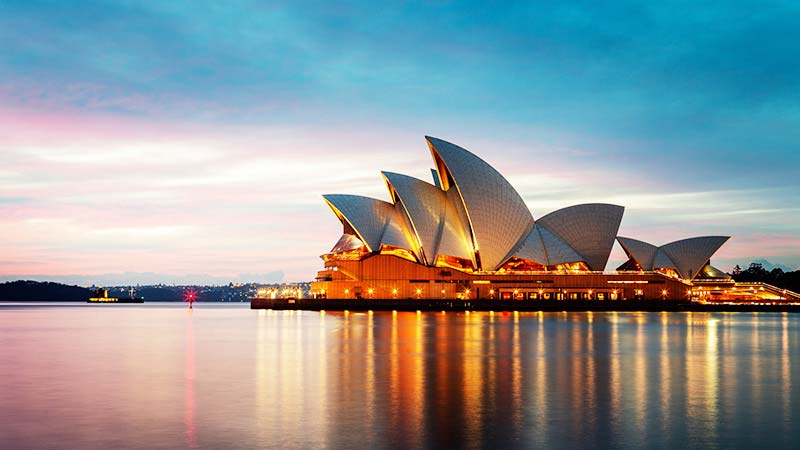 The Sydney Opera House, glittering with lights, at dusk.