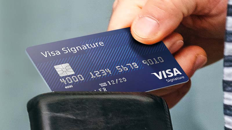 Hand holding a Visa Signature card.